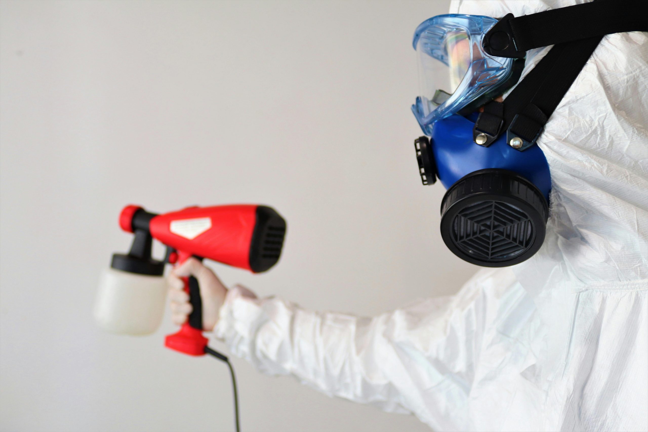mould removal expert in a full-body protective suit holding a sprayer