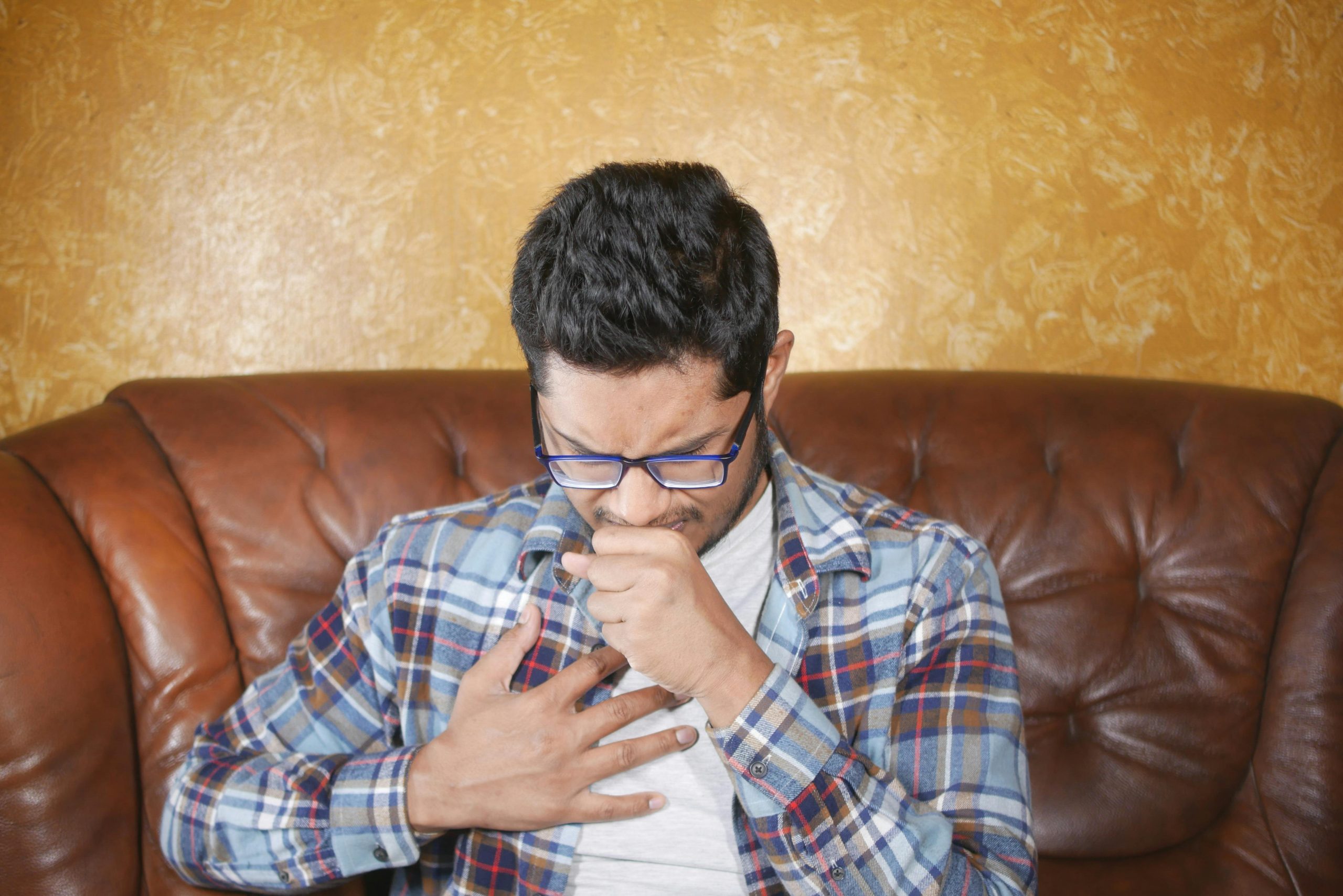 coughing man with his hand on his chest and the other hand over his mouth